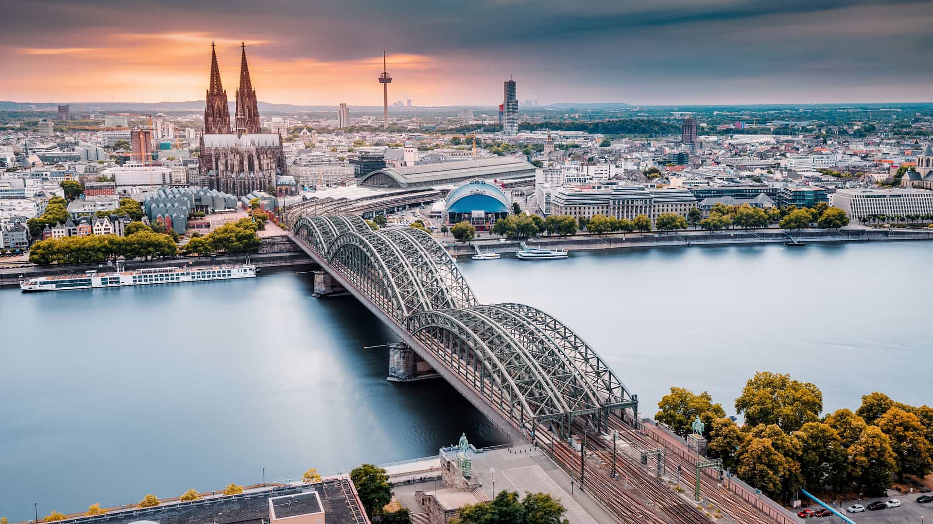Sunset view of the Rhine River with a historic arched bridge and cathedral spires, highlighting a scenic stop on Viking Ocean Cruises' European river excursions.