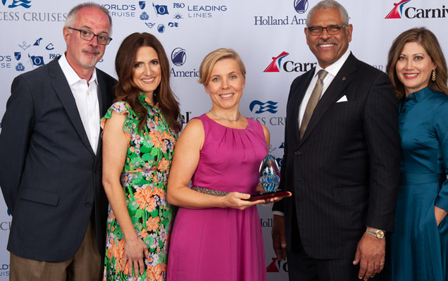 Woman in pink address poses with 4 Holland America Line executives with award.